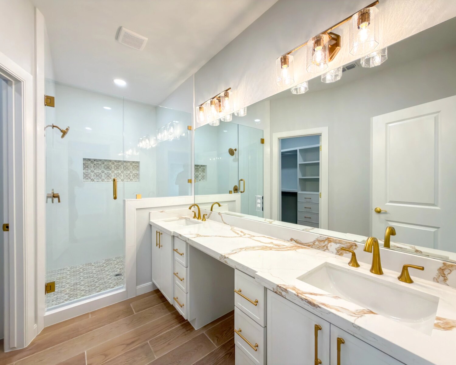 Primary bath with brass fixtures and calacatta marble double vanity