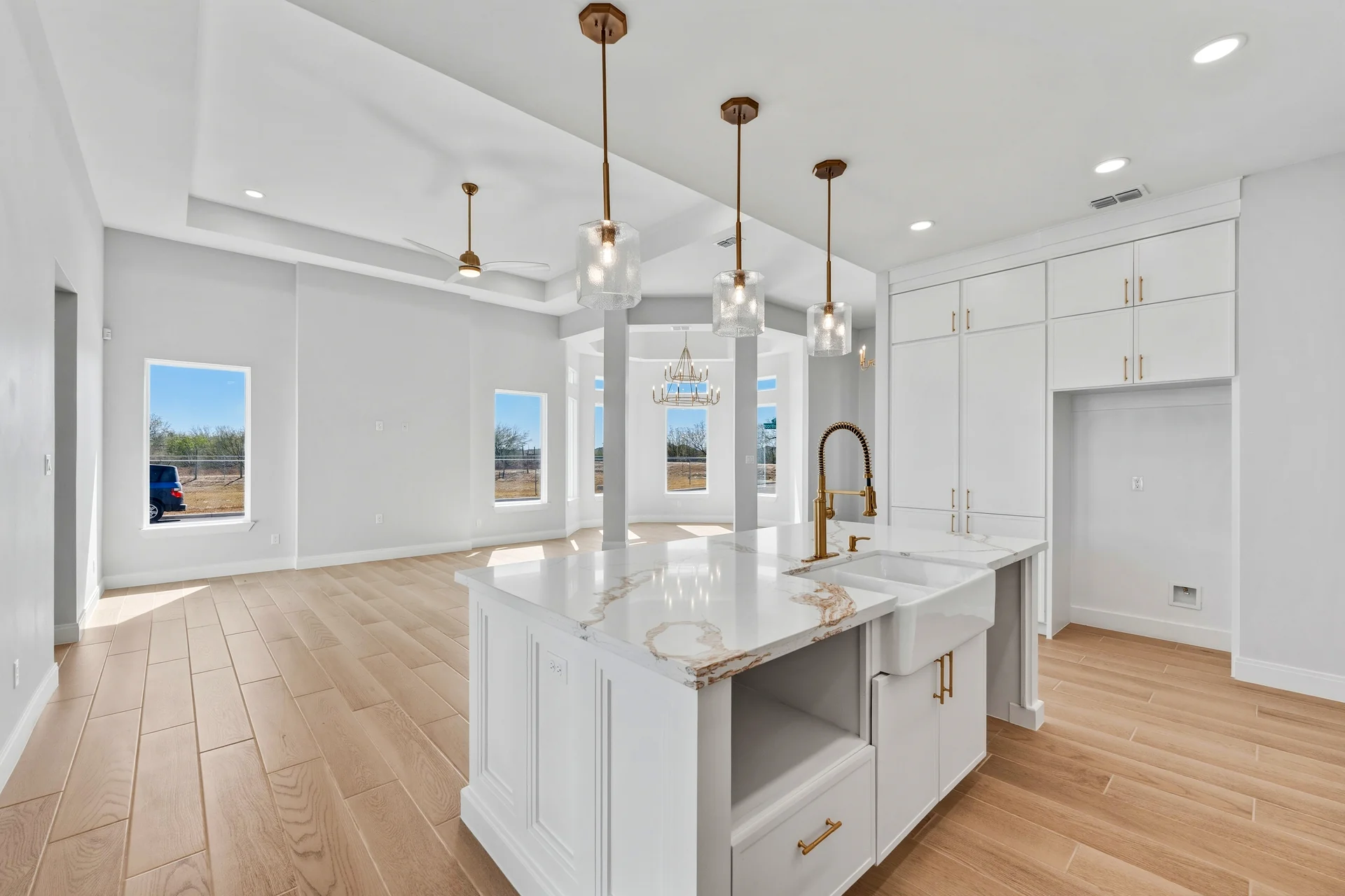 Open kitchen with marble waterfall island, brass pendants, and custom cabinetry — finished M Construction custom home